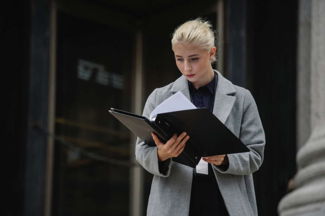 Image of a professional Woman reading documents from a folder.
